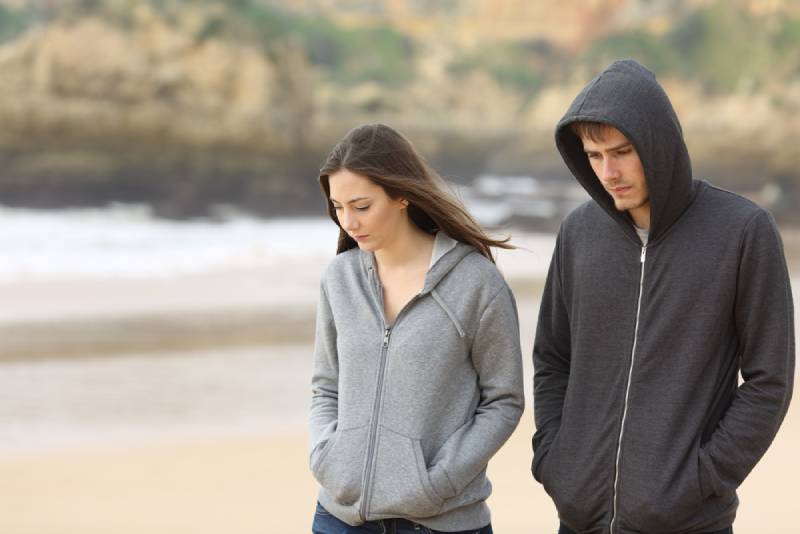 unhappy couple walking on the beach