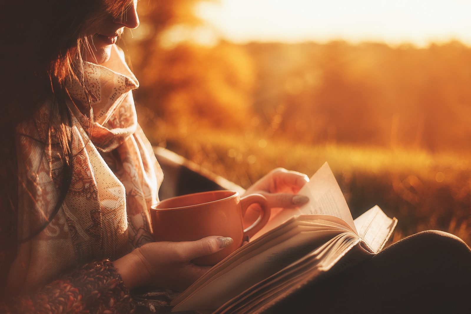 mujer leyendo un libro cubierta con una manta caliente