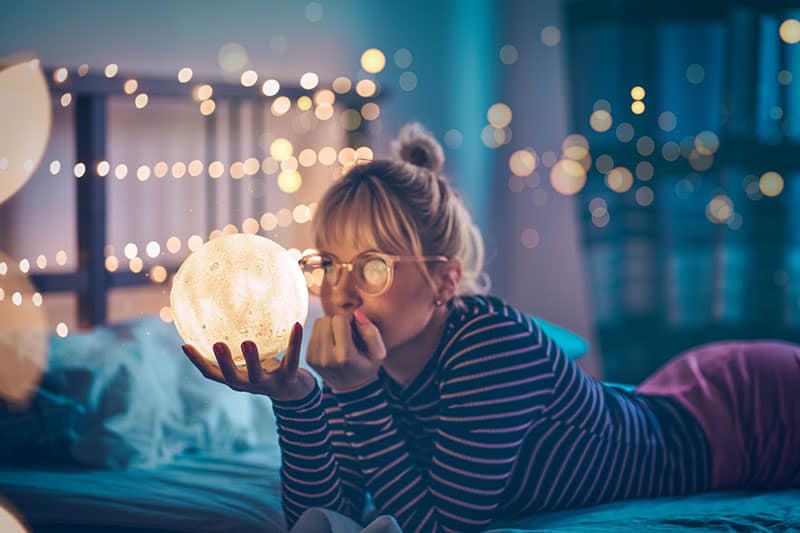 woman with glasses holding a light ball