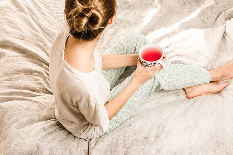 giovane donna che beve il tè nel letto