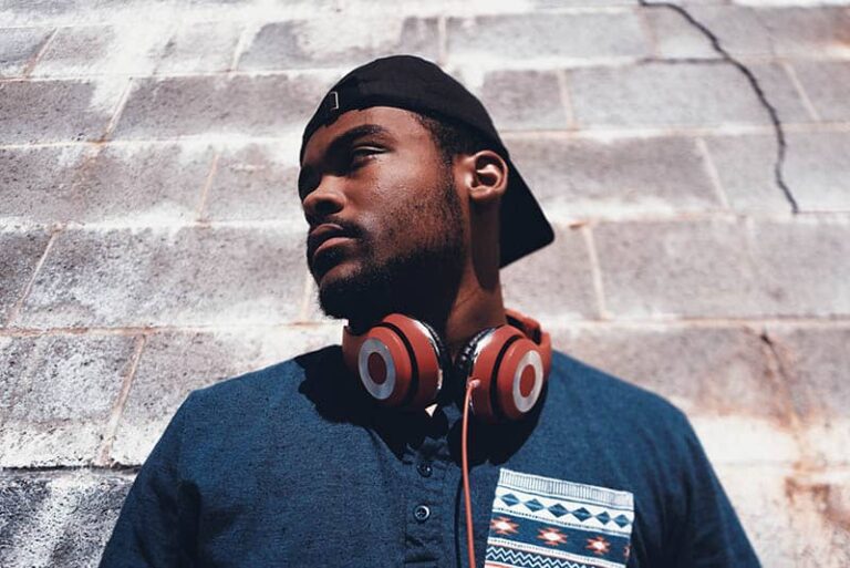 man wearing hat and headphones standing against wall