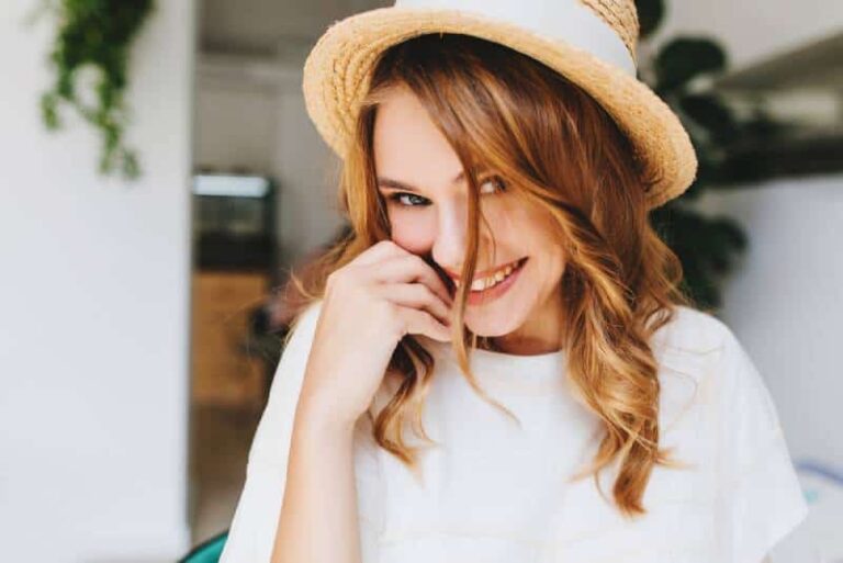 Ragazza sorridente e timida che indossa un cappello a casa