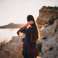 woman touches her hair in front of sea