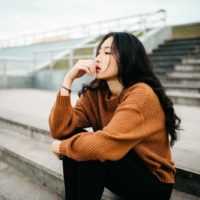 donna asiatica consapevole seduta all'aperto