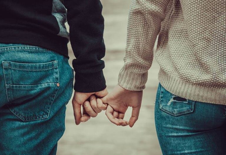 man holds woman pinky finger