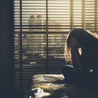 depressed woman sitting on bed