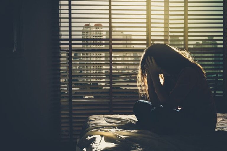 mujer deprimida sentada en la cama