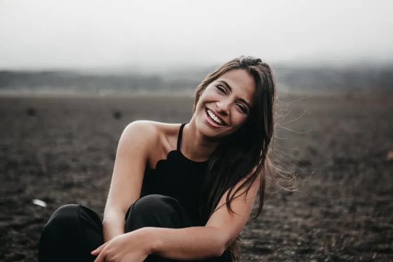 Woman smiles while sitting on the ground