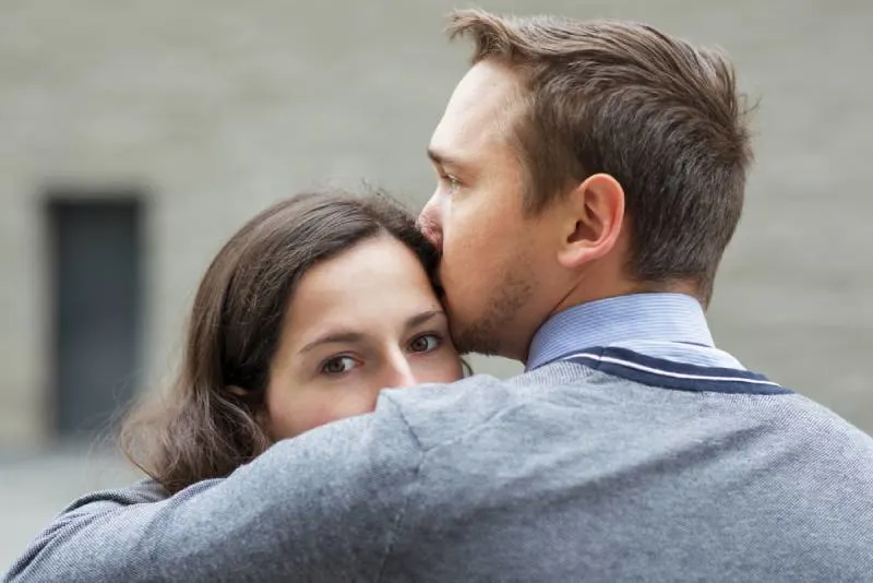 man kissing her worried girlfriend outside