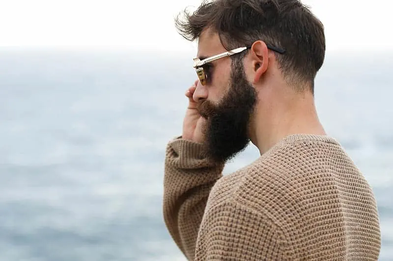 side view of bearded man wearing sunglasses and brown sweatshirt outside