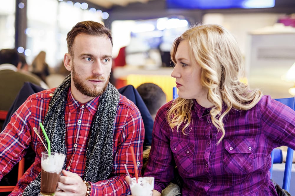 the man and woman sit as she watches him