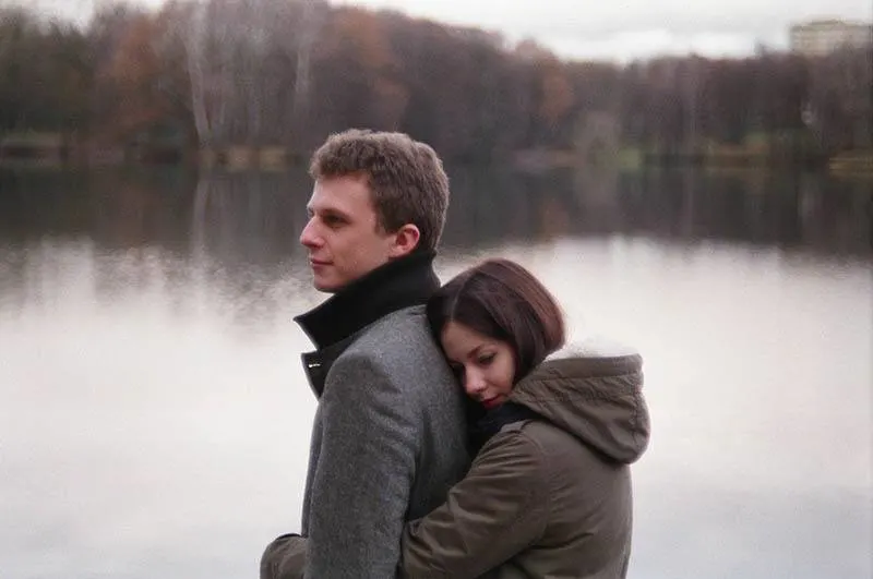 woman hugging man from back beside lake