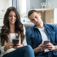 jealous man looking at woman typing