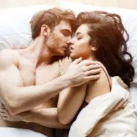 romantic couple kisses while lying on bed