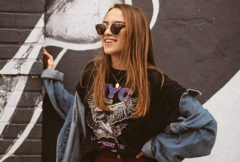 smiling woman wearing sunglasses in front of wall