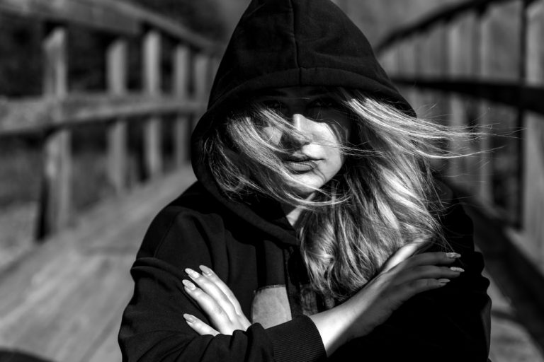 a blonde in the wind with a hood on her head stands