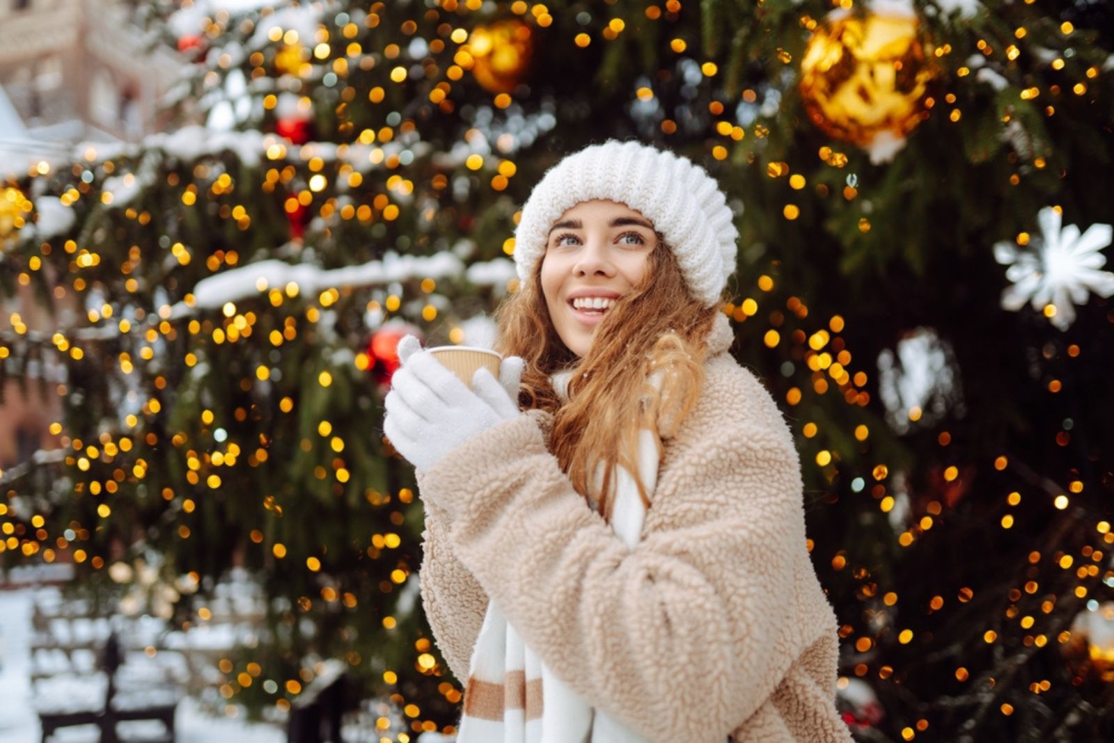 mulher sorridente com roupa de inverno segurando uma chávena