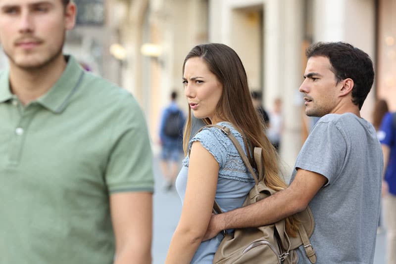 jealous man grabbing woman who turns for another man