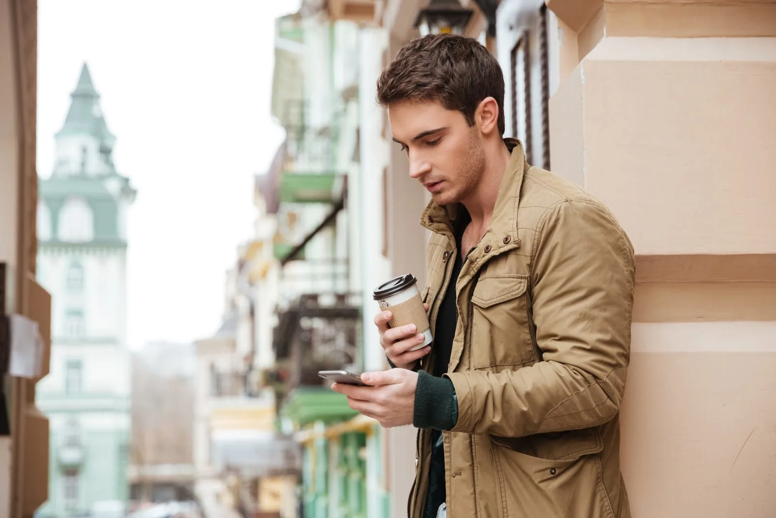 man holding cup of coffee and phone in his hands