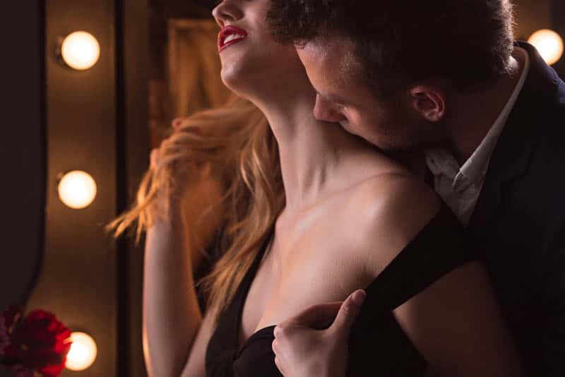 man kissing woman on neck