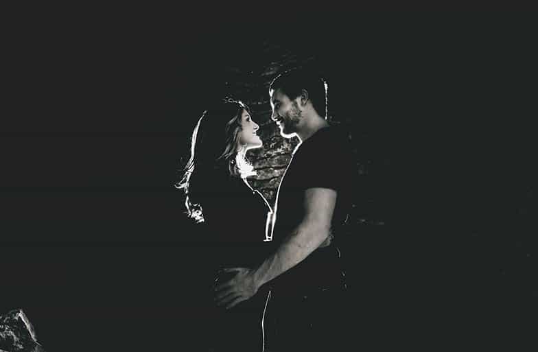 Couple hugging and smiling at each other in dark room
