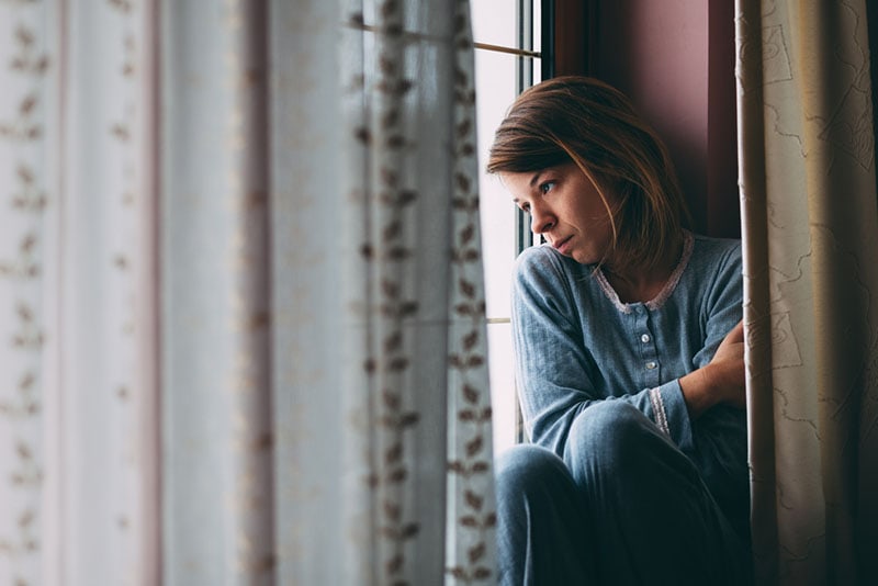 mujer triste sentada cerca de la ventana