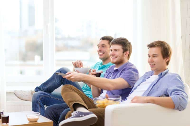 smiling man friends watching TV at home