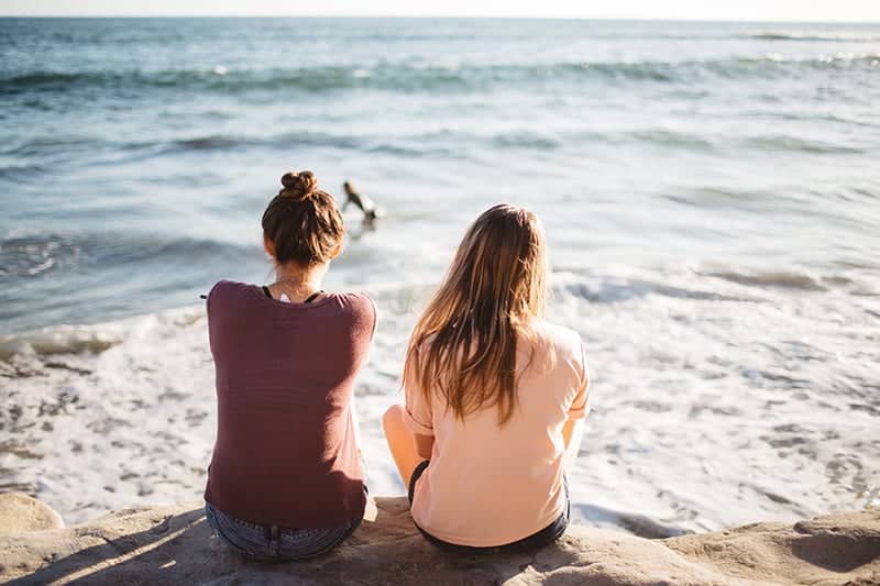 two female friends sitting on the beach