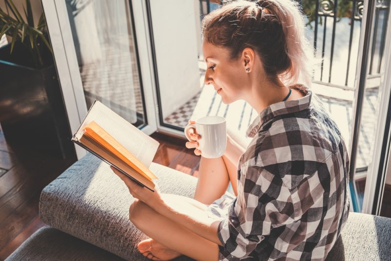 donna che beve caffè e legge un libro