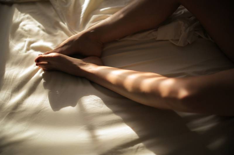 woman's feet on white bedspread