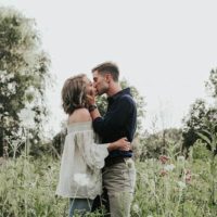casal romântico de pé e a beijar-se num campo relvado