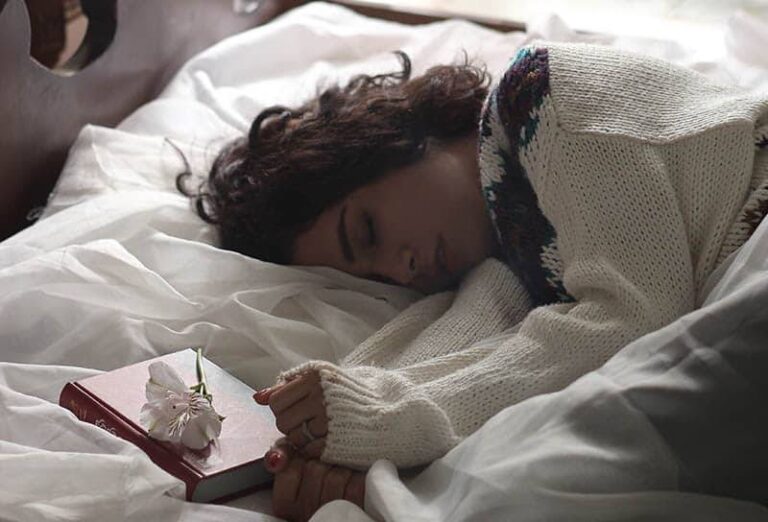 woman sleeping on bed beside book