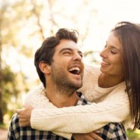 happy woman hugging smiling man from behind