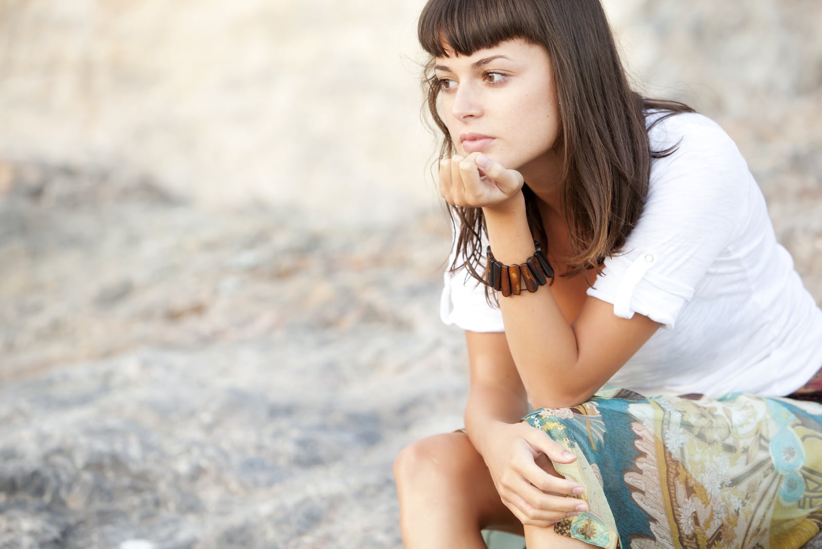 pensive brunette woman sitting outside