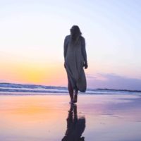 vista traseira de uma mulher a caminhar na praia