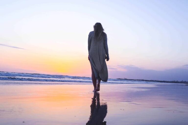 vista posteriore di donna che cammina sulla spiaggia