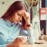 hermosa mujer joven y triste sentada y bebiendo café