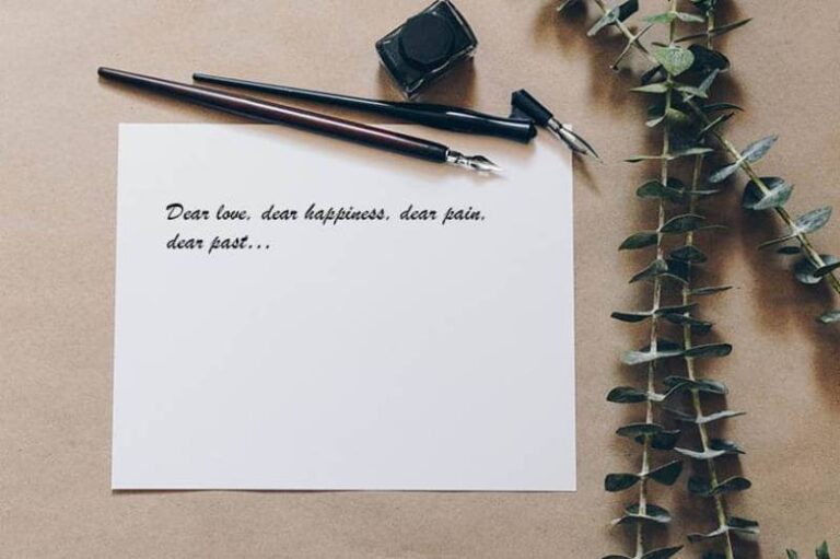 pen, letter and leafs on gray background