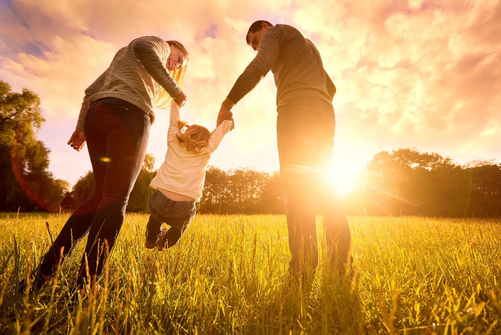 a man and a woman are playing in a field with a child