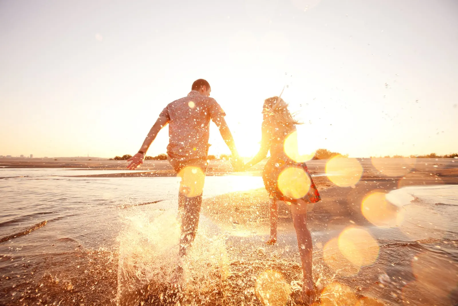 a man and a woman run along the beach holding hands