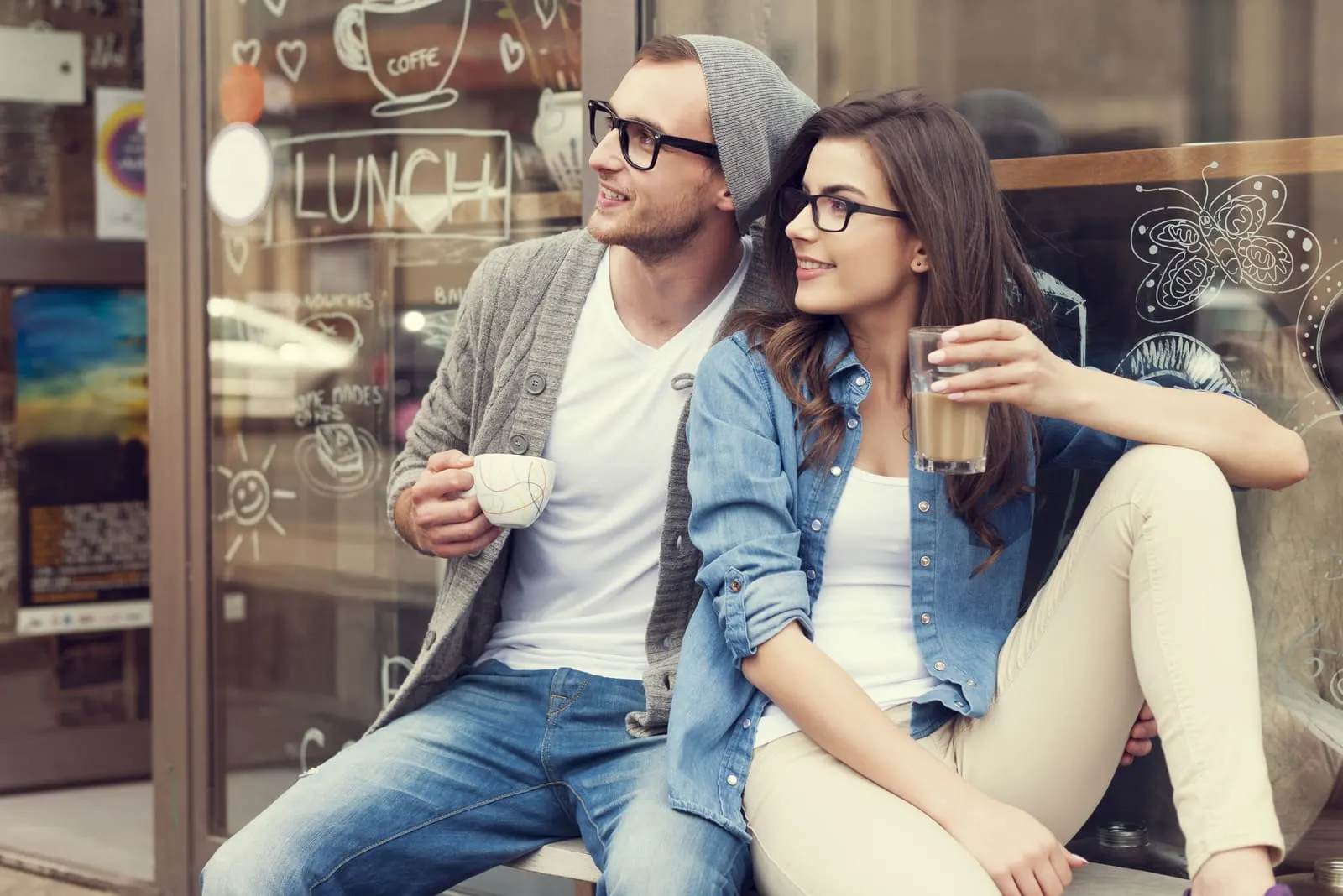 a man and a woman sit drinking coffee and looking away