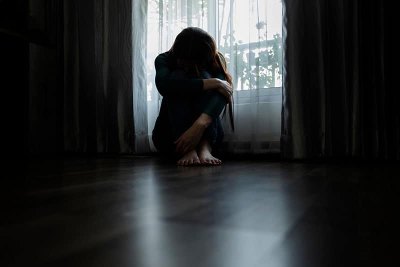 abused woman sitting on the floor in bedroom