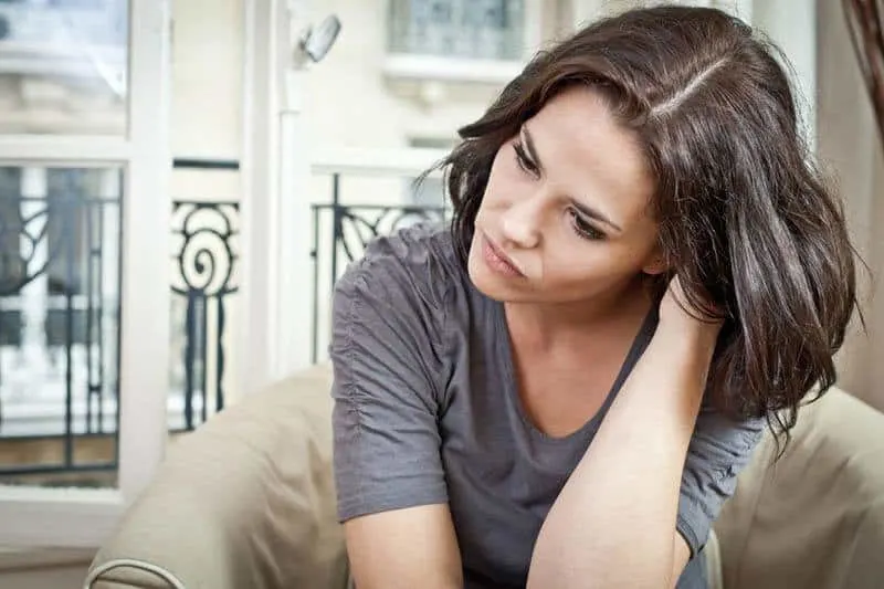 brunette woman sitting at home looks thoughtful
