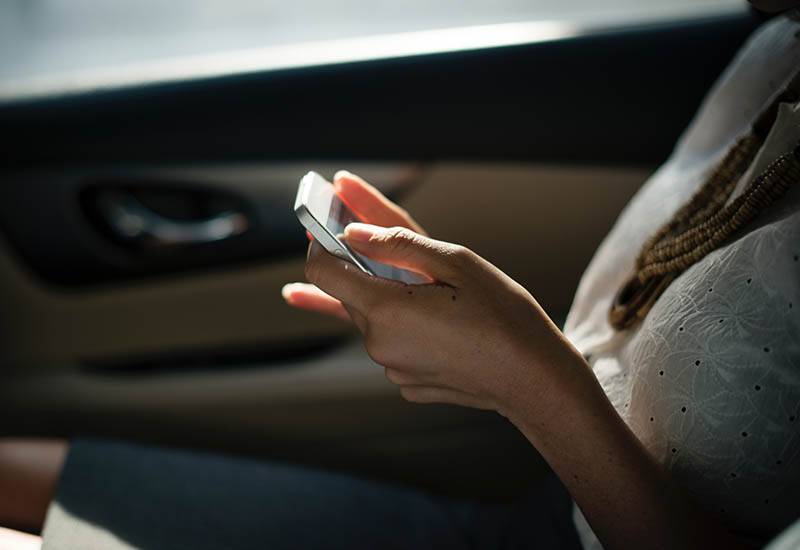 fotografia em grande plano de uma mulher a escrever no telemóvel no carro