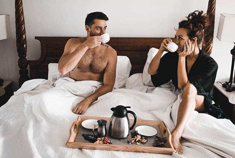 couple drinking coffee and talking on bed in morning