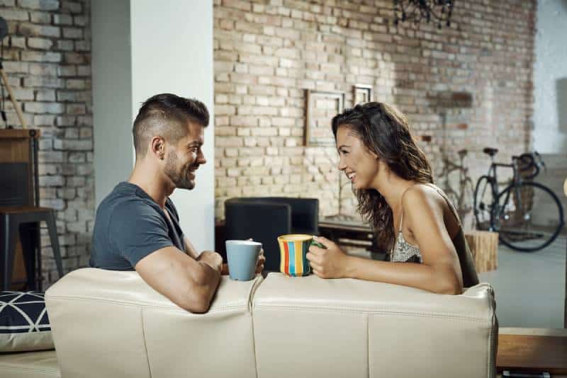 couple sitting in living room and talking with coffee