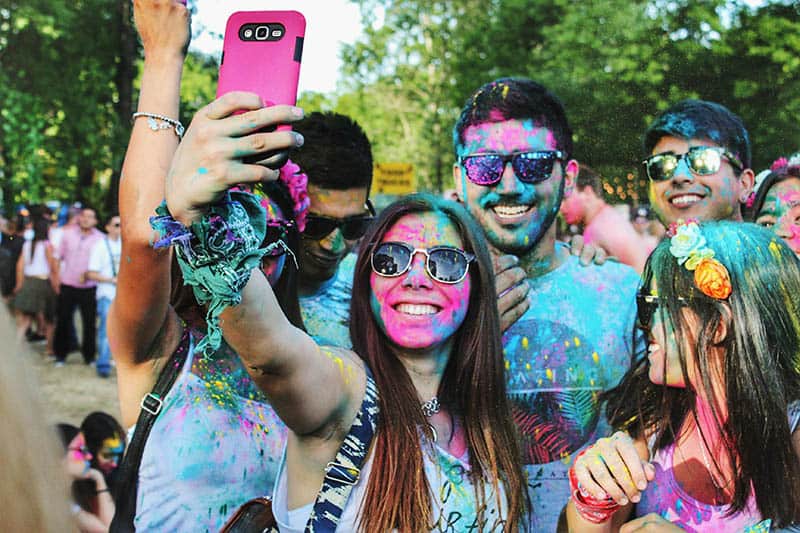 crazy friends covered with colors taking selfie
