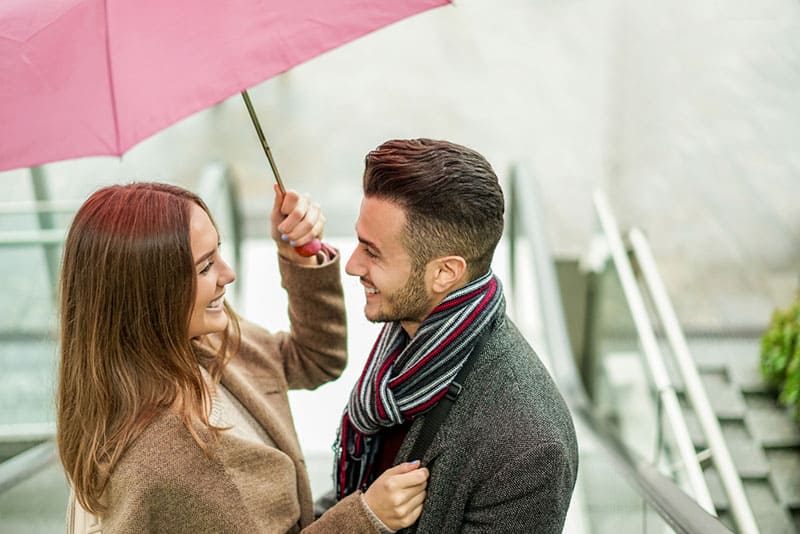 happy couple standing under umbrella