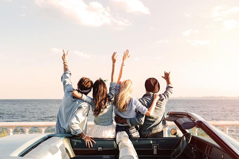 happy friends standing by the car