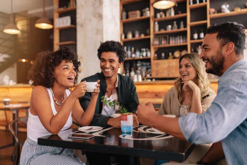 happy young friends having conversation at cafe